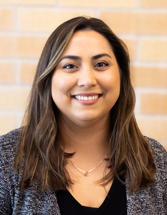 Photo of String Sprouts instructor Gabi Padilla Molina smiling in front of a brick background