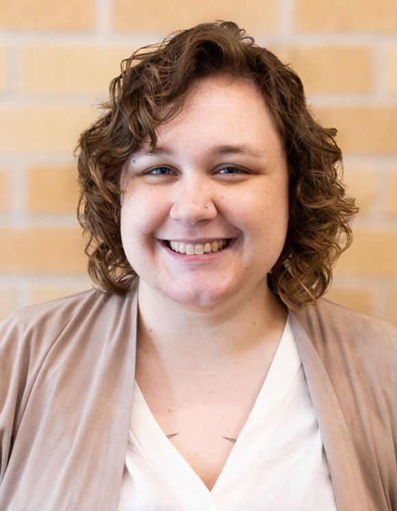 Photo of Michelle Metty smiling in front of a brick background